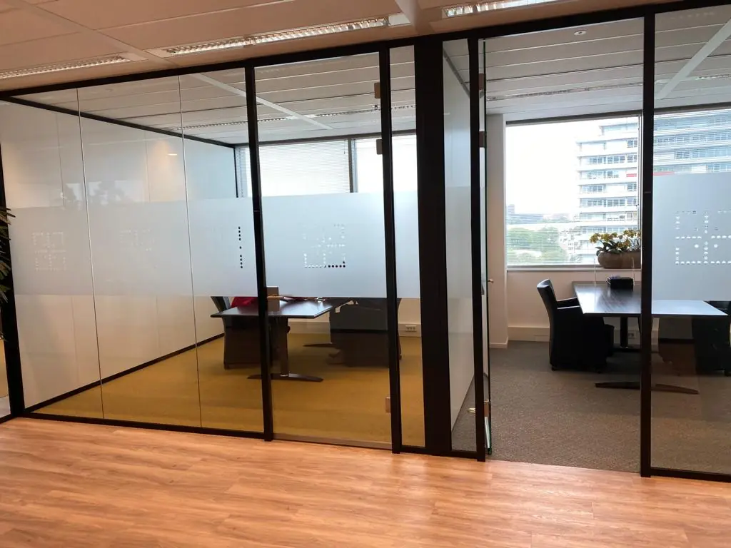 Moderne kantoorkamers met glazen wanden aan de Vliegend Hertlaan, uitzicht op kantoorgebouwen op de achtergrond.